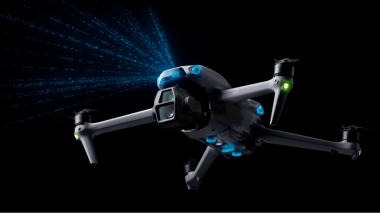 Квадрокоптер DJI Air 3S с включенными синими датчиками обнаружения и зелеными навигационными огнями на черном фоне, демонстрирующий возможности ночной съемки и безопасного полета в темноте